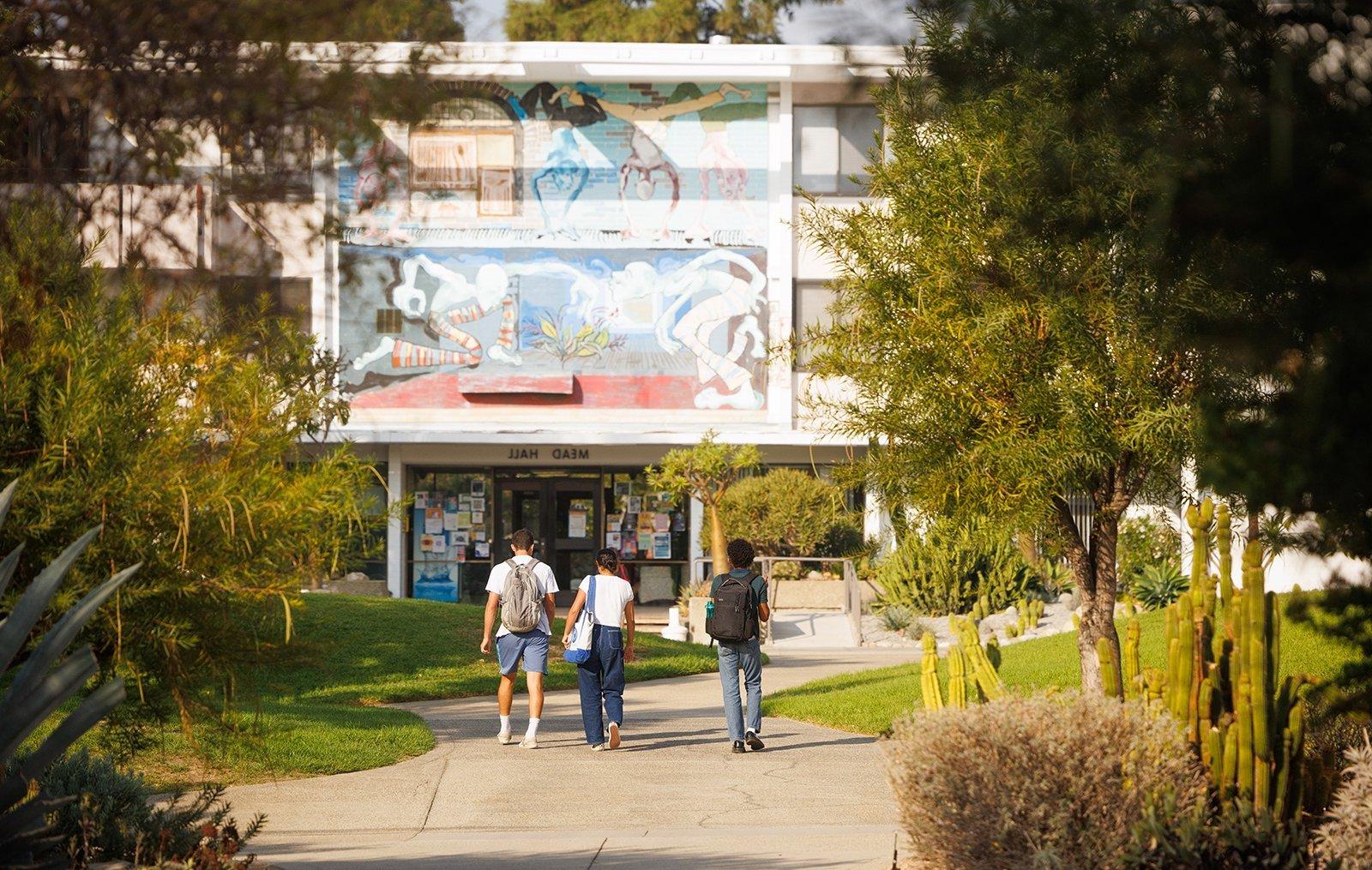 three students walk towards the entrance of mead hall